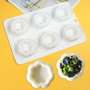 Detailed view of white 6-cavity silicone mold in flower pumpkin shapes on yellow backdrop