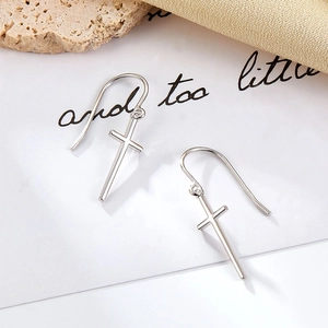 Detailed view of silver cross earrings with zircon stones on a decorative background