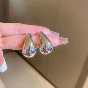 Detailed close-up of teardrop-shaped metallic earrings with a polished silver mirror finish