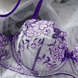 Detail of purple floral embroidery on lace bra with satin bow and sheer mesh