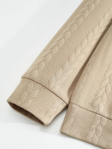 Macro detail of textured beige knit fabric with embossed cable stitch pattern