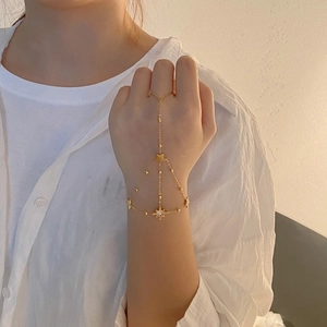 Detail of gold slave bracelet with star charms and crystal star on model's hand