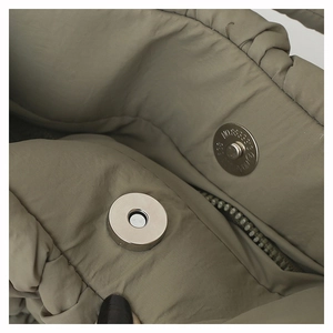 Detail view of khaki nylon puffer bag featuring a secure metal magnetic snap closure