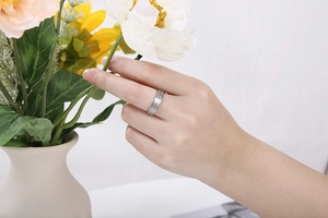 Detail of silver matte brushed stainless steel ring worn by model holding a flower