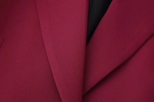 Dettaglio ravvicinato del rever del blazer bordeaux con trama di tessuto e fodera interna
