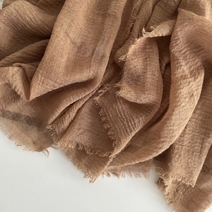 Detailed texture of brown linen cotton scarf featuring natural frayed edges and crinkled fabric
