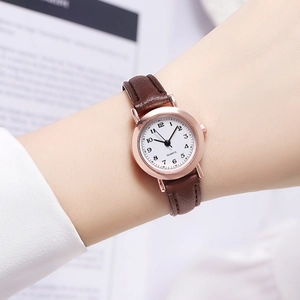 Close-up of elegant rose gold quartz watch with white dial and brown leather strap on wrist