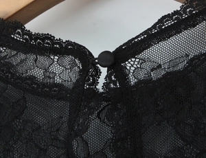 Macro view of eyelash lace neckline detail with button closure on a black slim lace top