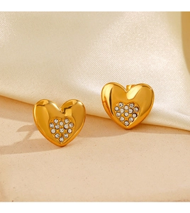 Dettaglio di orecchini a cuore placcati oro 18K con zirconi lucidi sulla seta