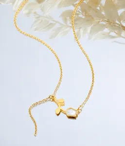 Macro detail of a gold tulip pendant necklace featuring white enamel flower petals