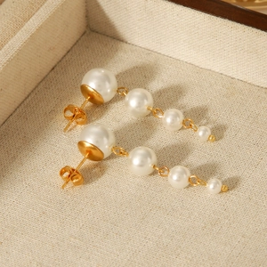 Detail of elegant French pearl earrings with gold plating on a beige linen jewelry tray