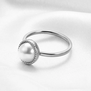 Macro detail of high-luster white pearl set in a beaded stainless steel ring bezel