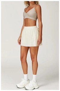 Dettaglio della gonna da tennis beige a vita alta con pantaloncino e reggiseno sportivo