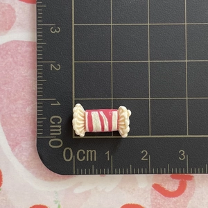 Makro-Detail von Miniatur 1,2 cm rosa Harz Bonbon Zubehör auf einer Metrikmatte