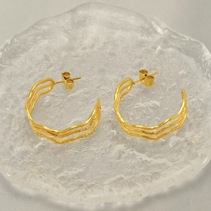 Detailed macro view of 18k gold plated stainless steel multi-layered wavy earrings