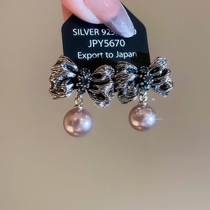 Gros plan sur des boucles d'oreilles nœud vintage avec perle rose et étiquette argent 925