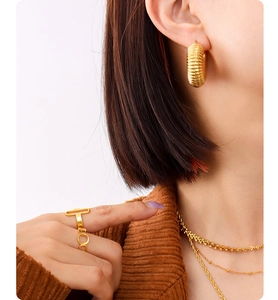 Detailed view of chunky ribbed hoop earrings and minimalist gold rings set on model