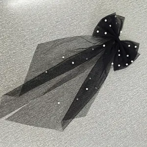 Detail of vintage black tulle bow hair clip with pearls and long veil for brides