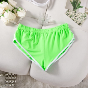 Flachliegende neongrüne Sportshorts mit weißem Rand und elastischem Bund auf weichem Grund