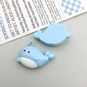 Detail view of cute light blue and white resin whale charms showing front and back