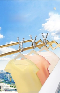 Detail of stainless steel windproof clothes pegs securely fixing shirts on a drying rack