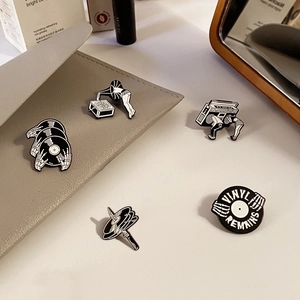 Lot de pins émaillés rétro noirs et blancs avec vinyles et têtes de mort sur un sac