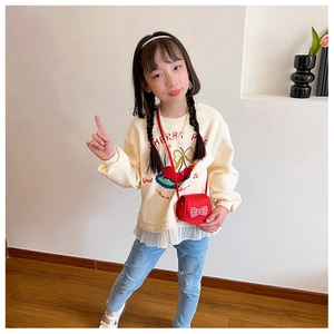 Kid modeling cute red mini crossbody bag with a bow and pearl chain on white sweater