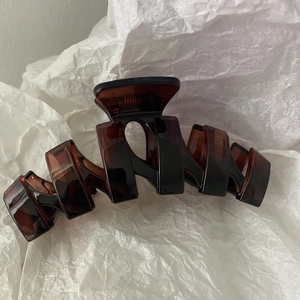 Close-up of a large tortoiseshell hair claw clip with a glossy amber finish and metal spring