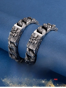 Close-up of gothic skull bracelet with heavy armor-style links on a blue pedestal