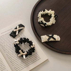 Dettaglio di elastici in raso arricciato e fermagli con fiocco in set bianco e nero