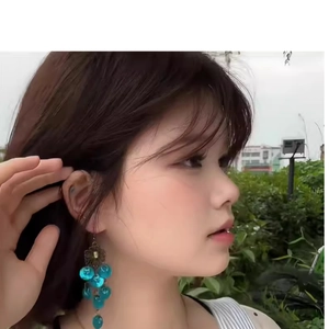 Detail of peacock blue shell tassel earrings in ethnic retro style on a model