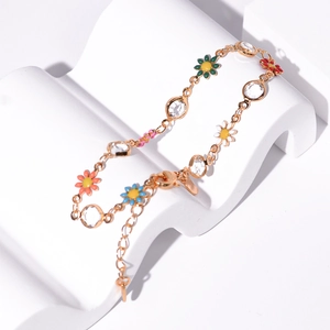 Detail of gold chain bracelet with colorful daisy charms and sparkling crystals