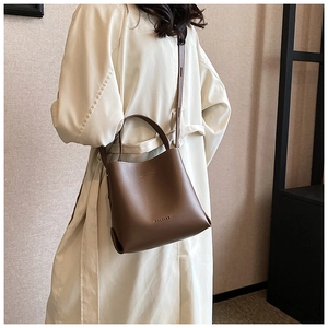 Detail of a brown leather bucket bag showing its textured finish and brand logo