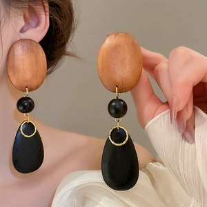 Detail of bohemian drop earrings with wood oval, black beads and golden metal rings