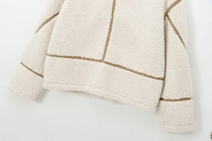 Gros plan détaillé de l'ourlet de la veste polaire crème avec bordure brune et texture