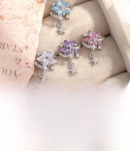 Detailed view of titanium steel star stud earrings in four colors on a velvet tray