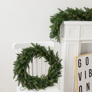 Deep green PE Christmas wreath and garland set with warm LED lights on a white fireplace