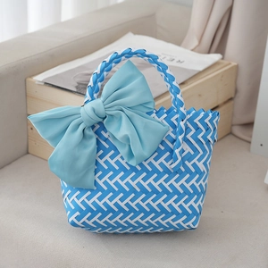 Detail of blue and white woven gift bag featuring a large decorative light blue silk bow