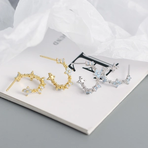 Detailed macro view of S925 silver C-shaped hoop earrings with blue opal flower stones
