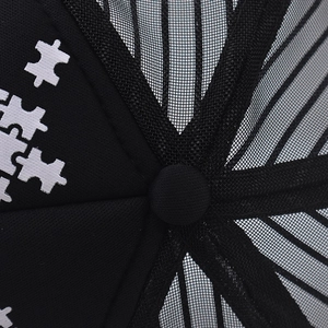 Close-up of black mesh trucker hat crown showing breathable net and top button detail