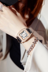 Detail of rose gold square watch with crystal bezel and black Roman numerals on white dial