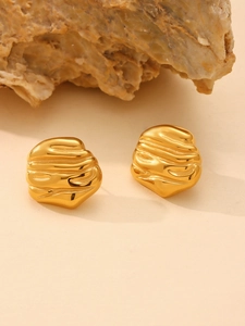 Macro shot of gold stainless steel earrings with irregular geometric textured wave surface