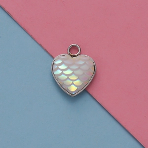 Dettaglio macro del ciondolo a cuore con scaglie bianche iridescenti e cornice in metallo