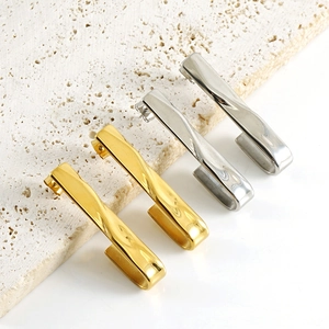 Detailed view of U-shaped stainless steel earrings in gold and silver finishes on stone