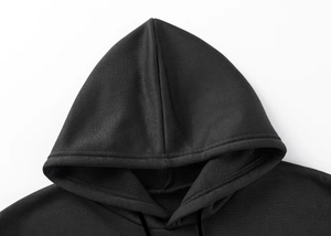 Detailed close-up of the double-stitched hood seam on a black cotton hoodie