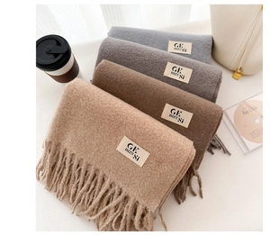 Macro detail of stacked cashmere-feel fringe scarves in beige, brown, and grey tones