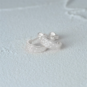 Close-up of 925 sterling silver star-shaped C-hoop earrings with pavé set crystals