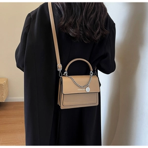 Model view showing the khaki crossbody square bag with a silver chain and pendant