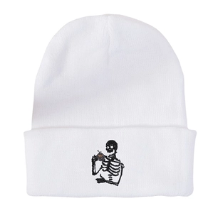 White knitted beanie with skeleton holding coffee embroidery on a plain background
