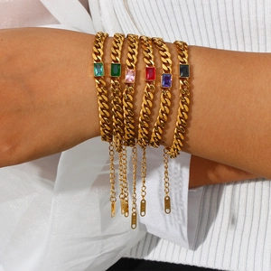Dettaglio di bracciali a catena cubana dorati con pietre rettangolari in zircone colorate